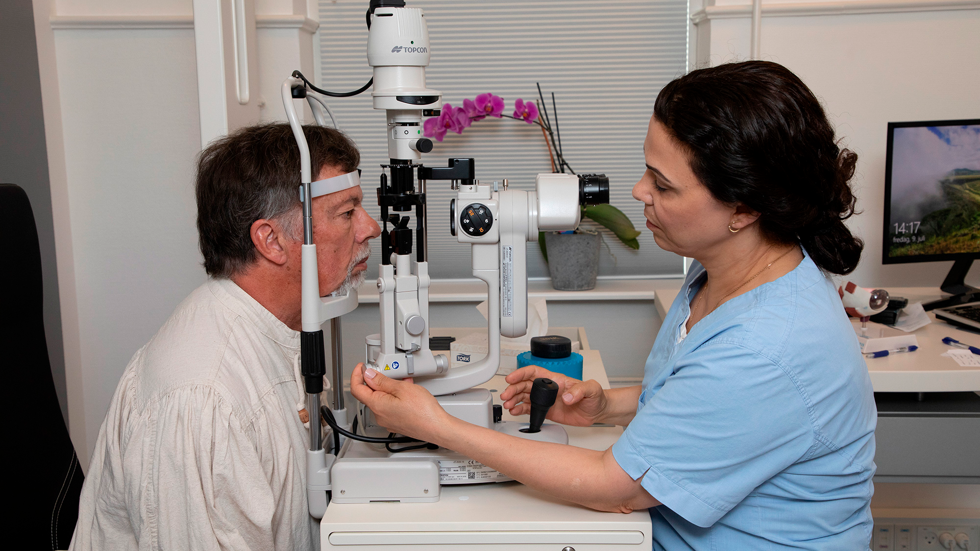 En mand får en øjenundersøgelse af en kvindelig optiker ved en moderne øjenklinik.