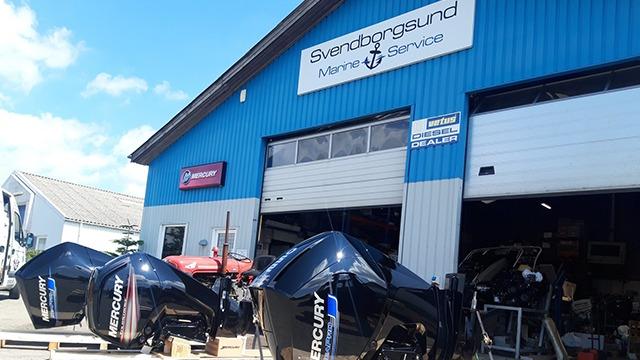 Bådserviceværksted med to Mercury motorer foran en blå bygning med skiltet "Sverdrupsgund Marina Services".