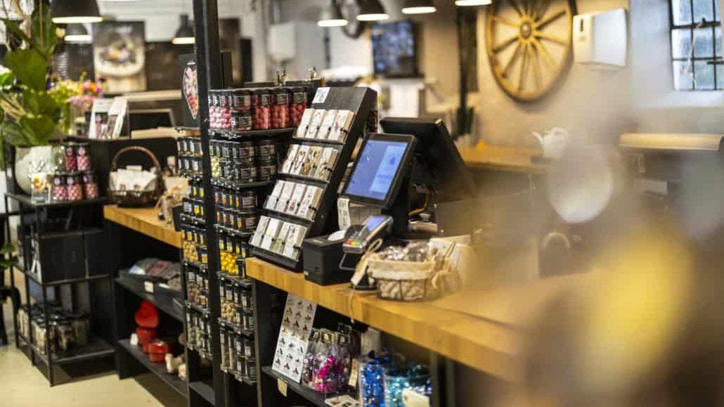 Inde i en butik med en kasse og hylder fyldt med forskellige varer og dekorationer.