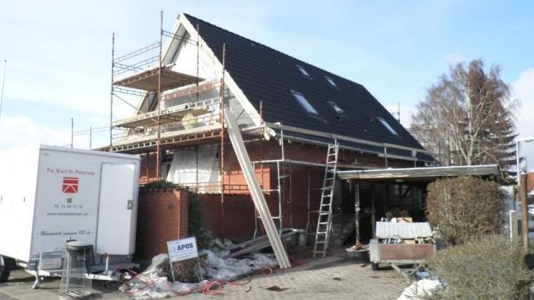 Hus under renovering med stillads, stiger og byggeaffald foran.