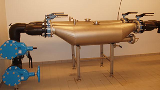 Et stort røranlæg med metal- og plastkomponenter, der bruges til vandbehandling i en industriel installation.