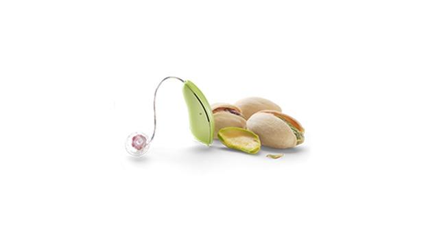 Et pistacie med skallen åben, en grøn skald og flere pistacienødder på en hvid baggrund.