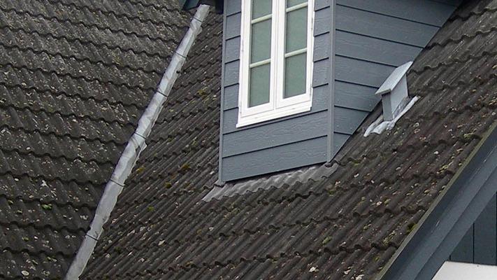 Tag med grå tegl og et vindue i en karnap på en moderne bygning.