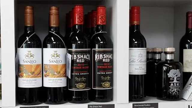 Flasker med rødvin på en hylde, herunder mærkerne San Diego og Rib Shack Red.