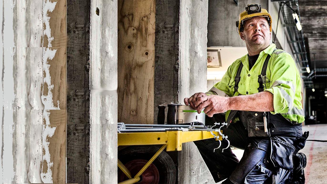 En bygningsarbejder i sikkerhedstøj arbejder med værktøj på en byggeplads.