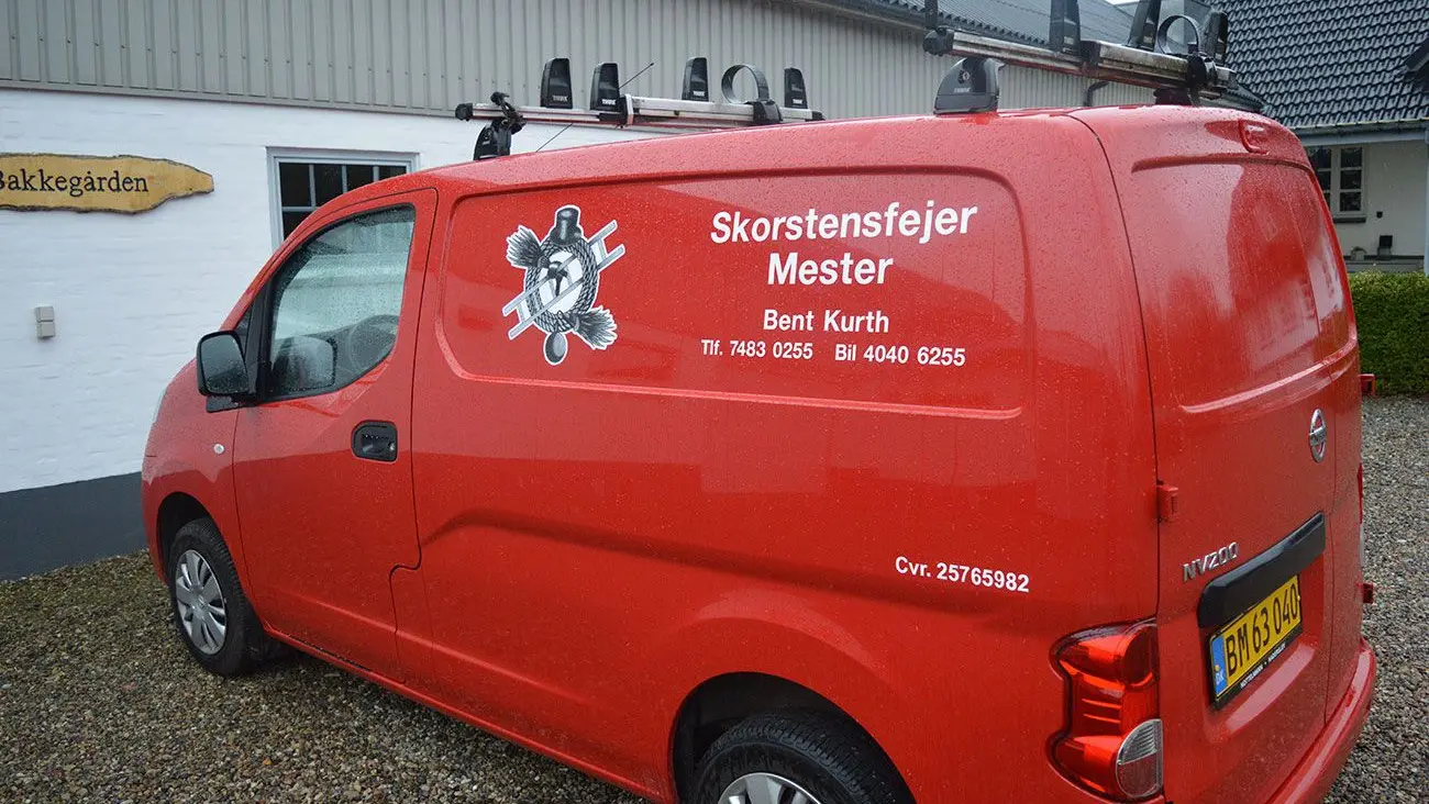 Rød varevogn med teksten "Skorstensfejer Mester" og kontaktinformation på siden.