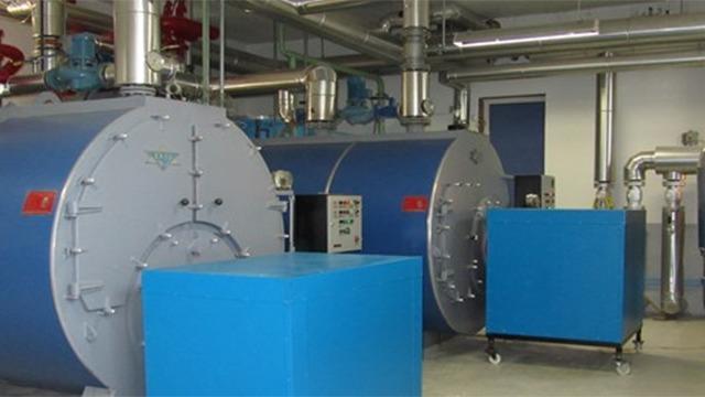 To store energi i store blå kedler i et moderne teknisk rum med rør og ventiler.