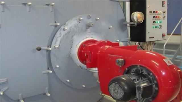Rød motor med ventilator i en industriel maskine, der viser kontrolpanel og rørforbindelser.