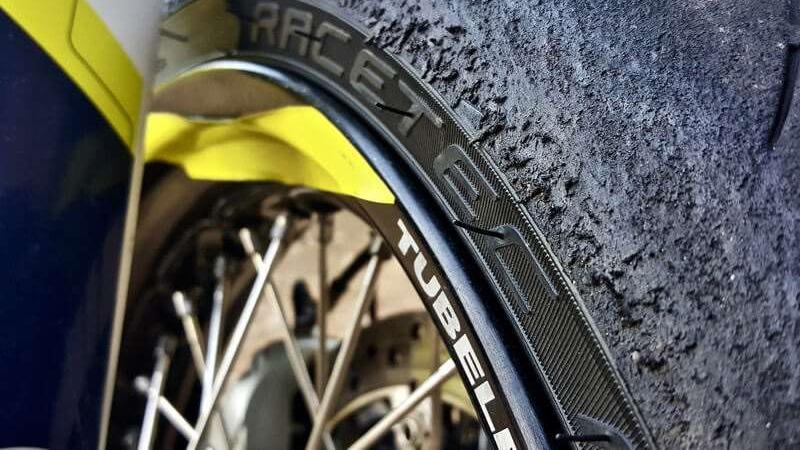 Nærbillede af et racerdæk med slidbanemønster og carbonfiberfælg på en motorcykel.
