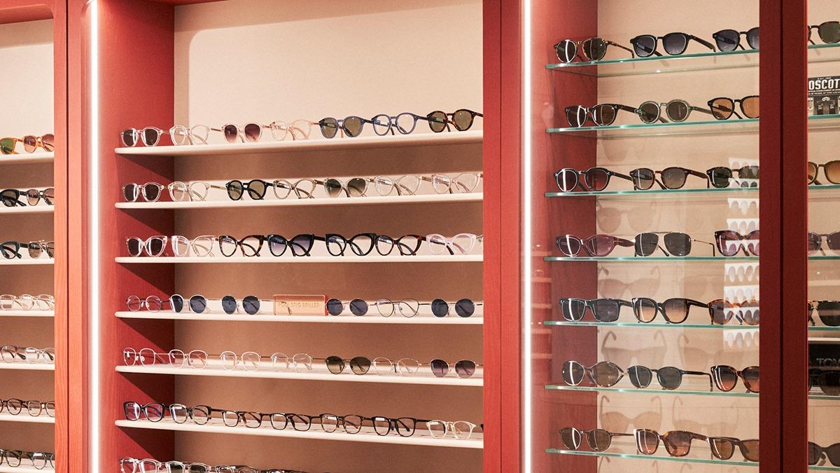 Et udvalg af solbriller præsenteret på hylder i en optikerbutik.