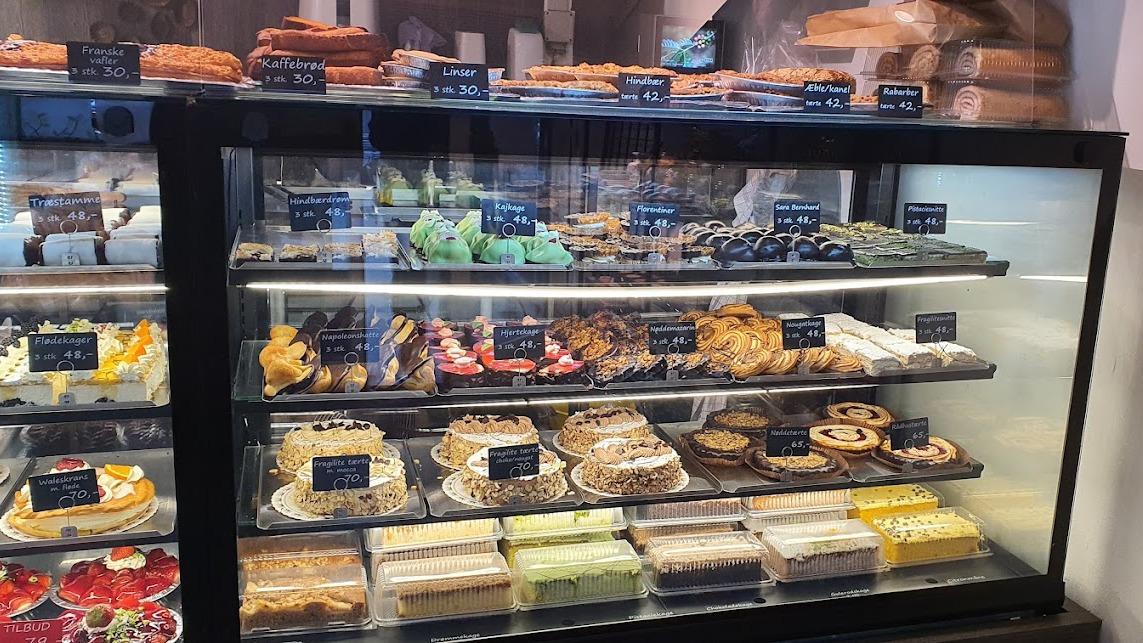 Et udvalg af lækre kager og bagværk i en bageridisplay med farverige desserter og småkager.