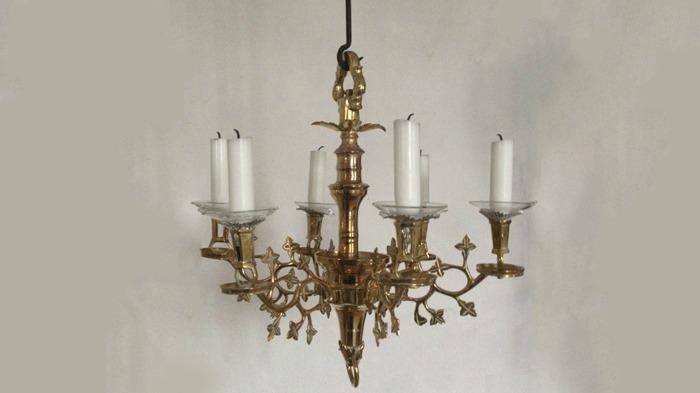 En smuk lysekrone i guld med seks lysestager og detaljerede blade.