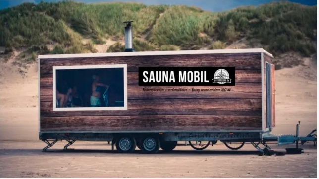 En mobil sauna på en strand, med træbeklædning og vindue, hvor folk slapper af indeni.