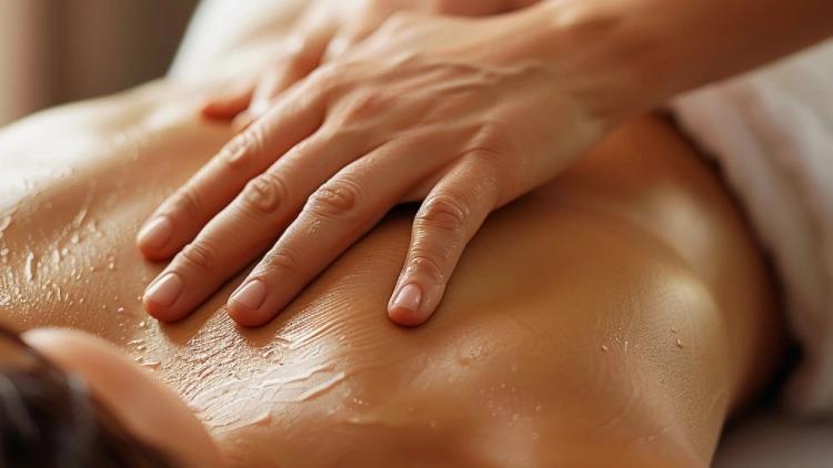 En person får en afslappende rygmassage med olie i et lyst rum.