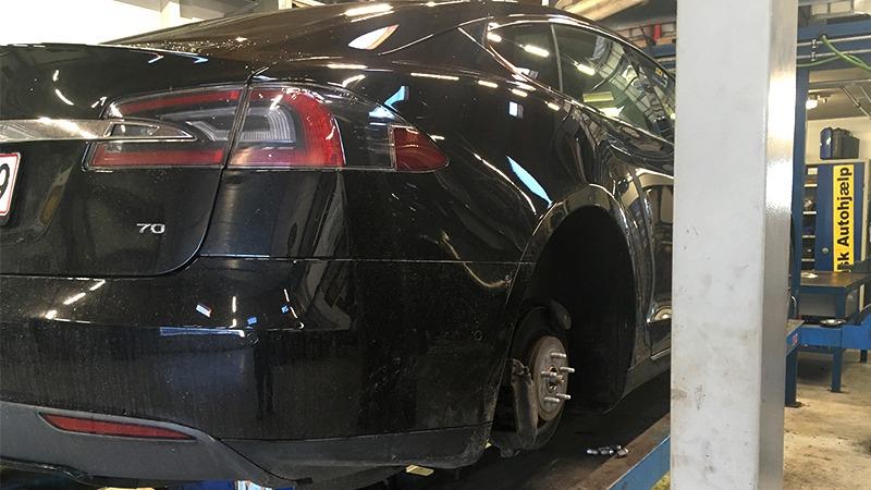 En sort Tesla Model S på en lift i et autoværksted, klar til reparation og vedligeholdelse.