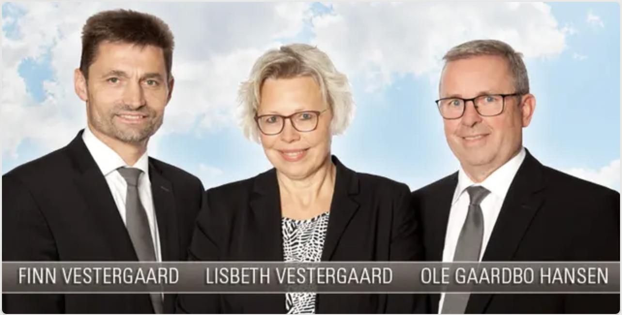 Tre professionelle personer står sammen foran en lys himmel, iført formelle jakkesæt og smilende.