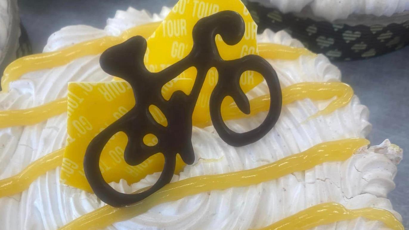 En kage med flødeskum, pyntet med en chokoladecykel og gule frugtskiver.