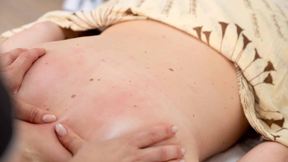 En person får en afslappende rygmassage med fokus på velvære og stressreduktion.