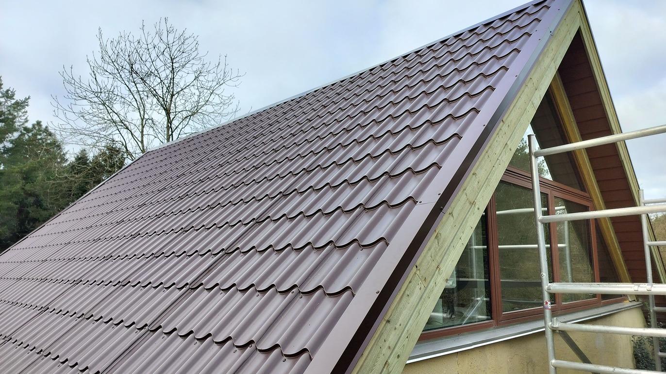 Taget på et hus med brune tagplader og en træramme, set fra en skrå vinkel.