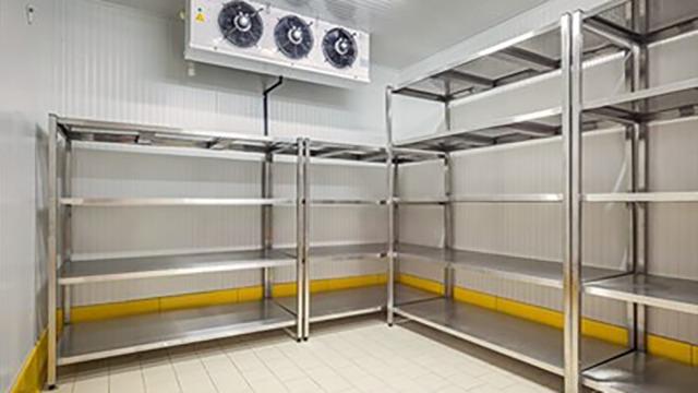Tom opbevaringsrum med metalhylder og et ventilationssystem i loftet.