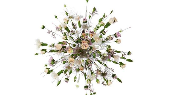 En farverig buket med forskellige blomster, herunder roser og nelliker, arrangeret i en smuk form.