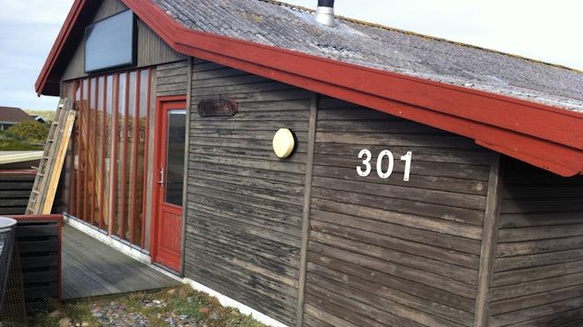 Hus med rød tag og træfacade, nummer 301, beliggende i et roligt område.