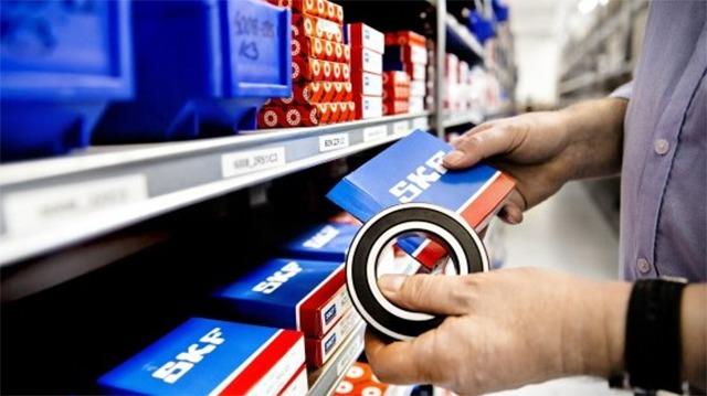 En person tager en pakke fra en hylde i et lager med blå kasser og reservedele fra SKF.