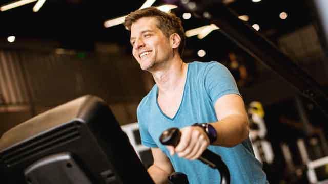 Mand træner på en motionsmaskine i et moderne fitnesscenter.