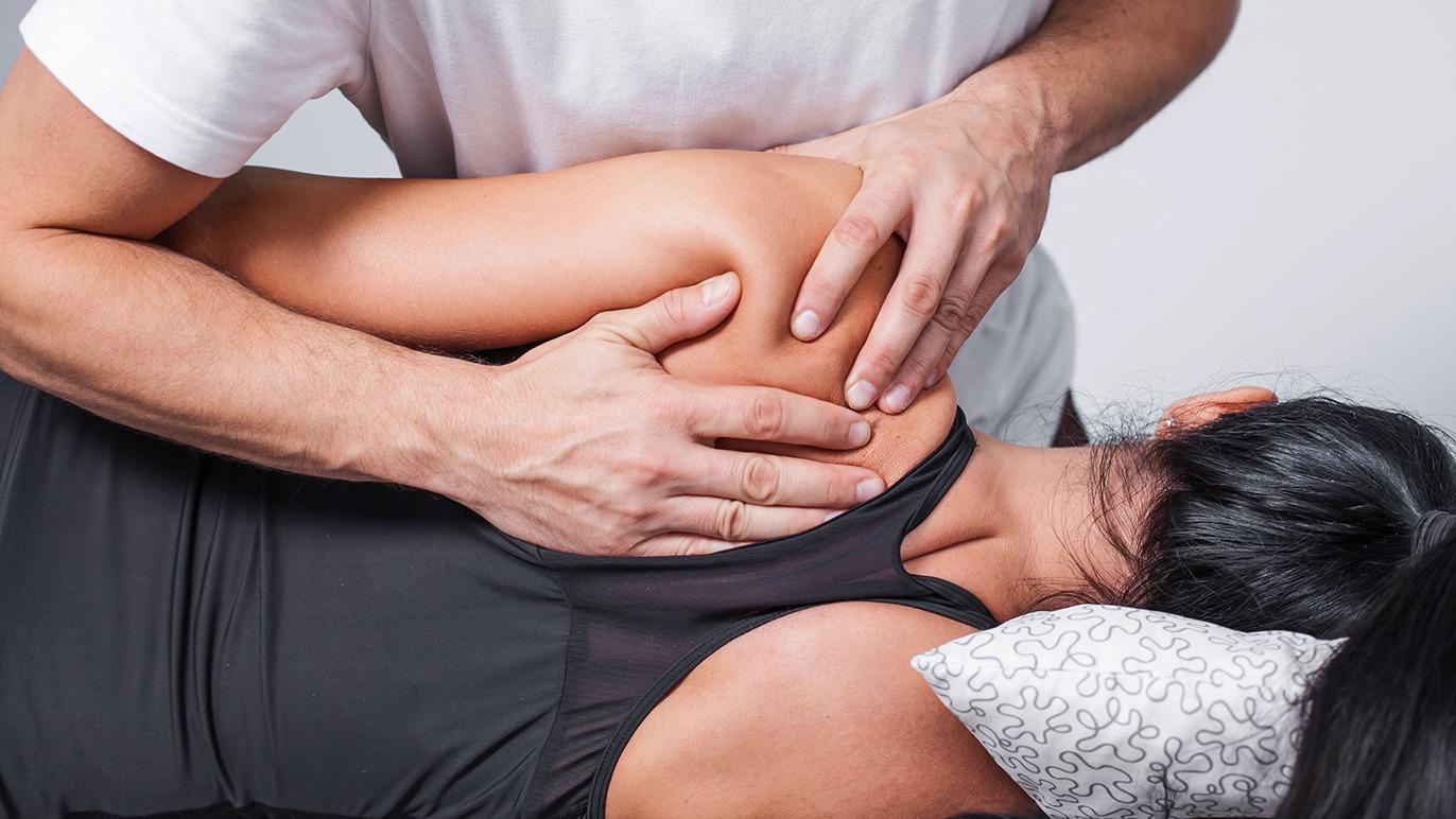 En massør giver en afslappende rygmassage til en kvinde, der ligger på en massagebriks.