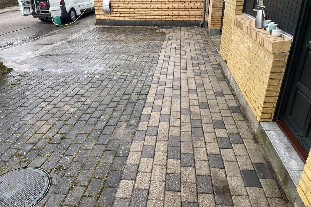 Belægning af brosten på en indkørsel med en blanding af grå og beige farver.