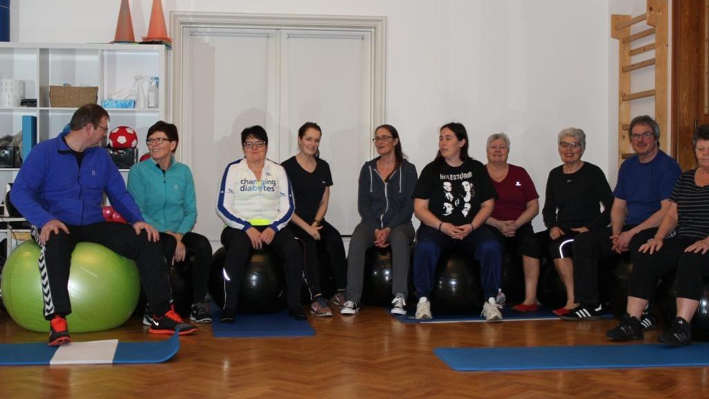 Gruppe af mennesker, der deltager i en træningssession på fitnessbolde i et indendørs træningslokale.