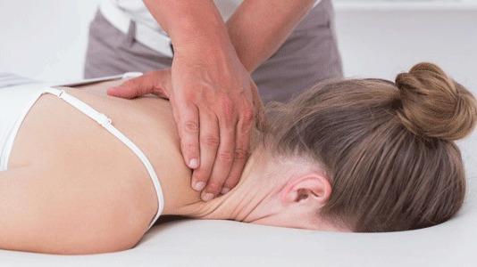 En massør giver en afslappende massage til en kvinde, der ligger på maven med ansigtet nedad.