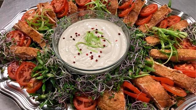 En smuk anretning med sprøde brødskiver, tomater, asparges og en skål med lækker dip i midten.
