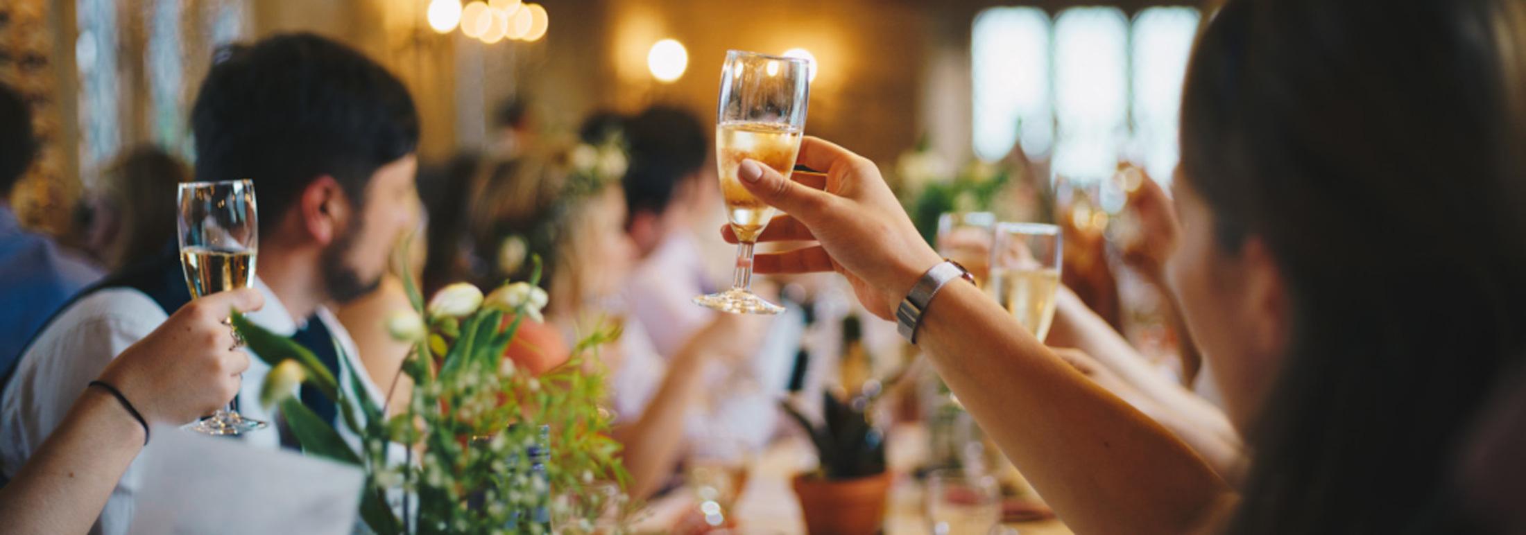 En festlig middag med gæster, der skåler med champagneglas og blomsterdekorationer på bordet.