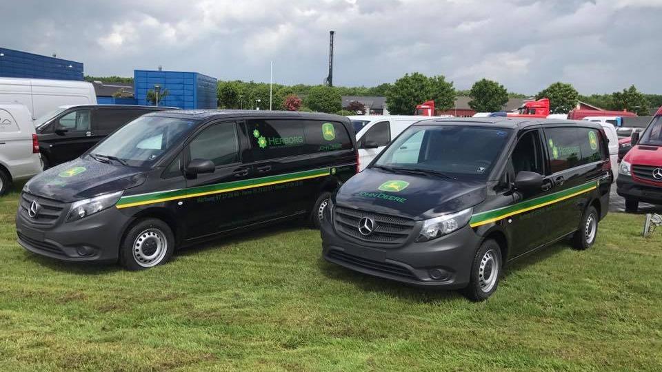 To biler fra Mercedes-Benz parkeret på en græsplæne, begge med grønne og gule striber.
