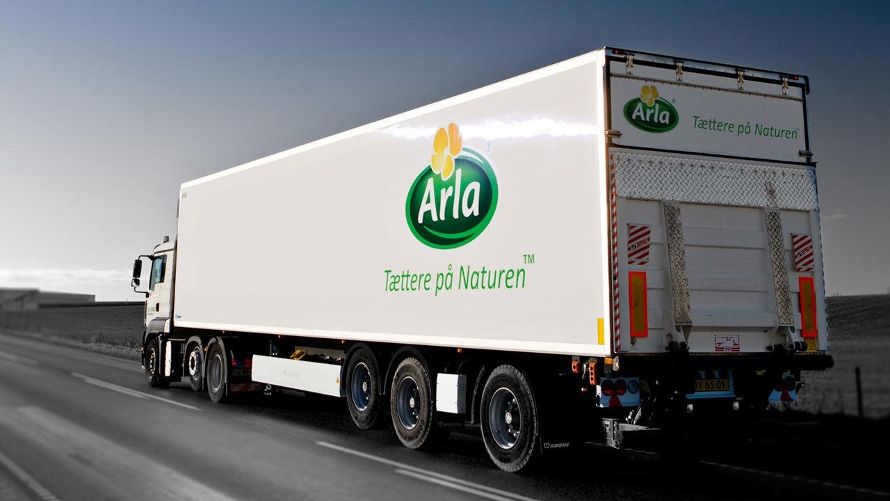Lastbil med Arla-logo, der kører på en vej, med fokus på bæredygtighed og naturprodukter.