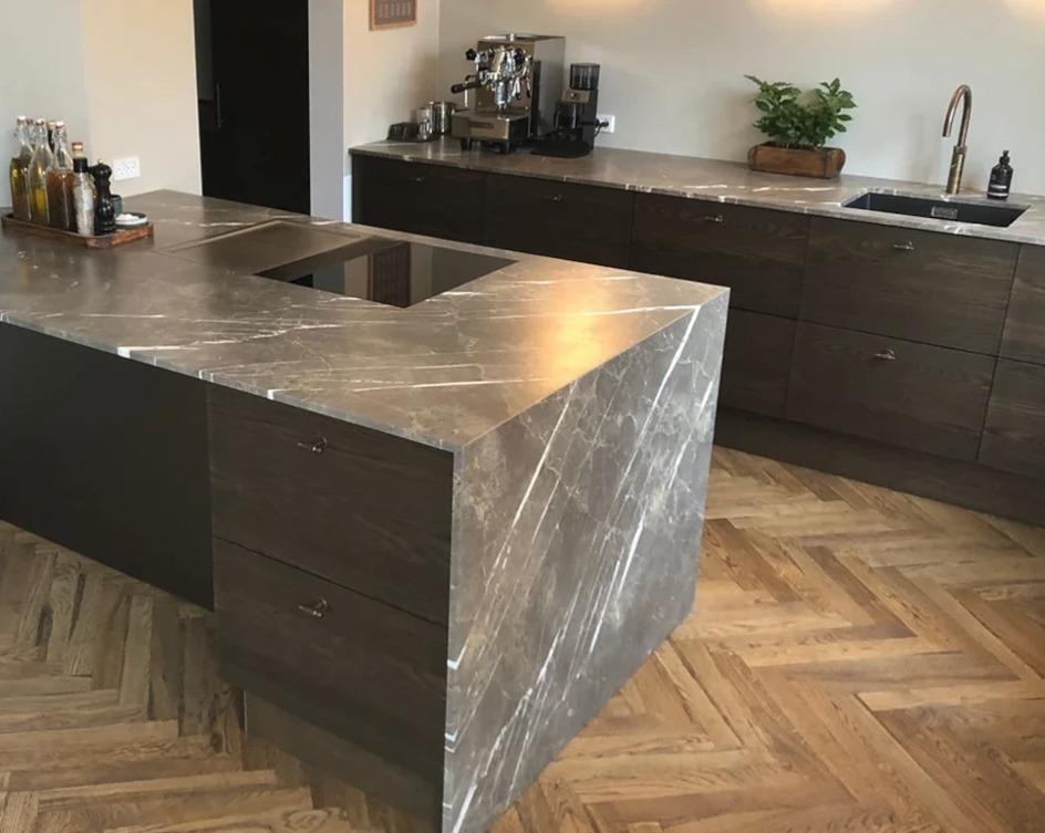 Moderne køkken med en marmorø og mørke træskabe, der har en elegant og stilren indretning.