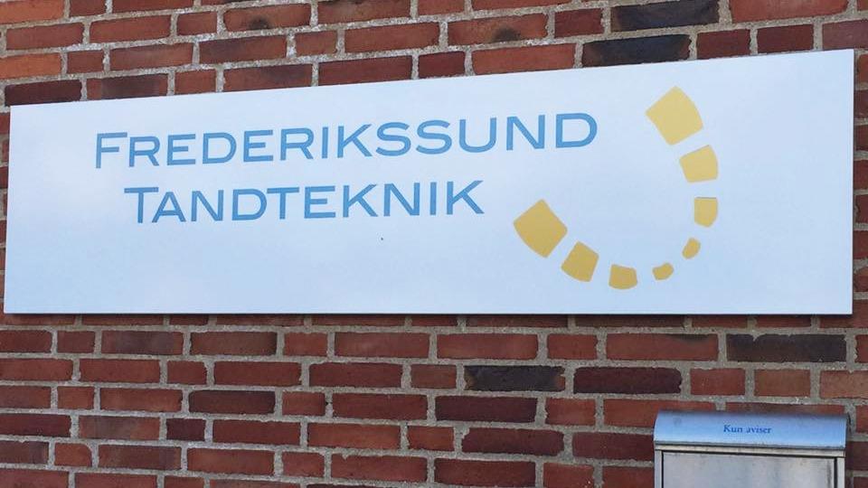 Frederikssund Tandteknik skilt på murstensvæg med postkasse i bunden.