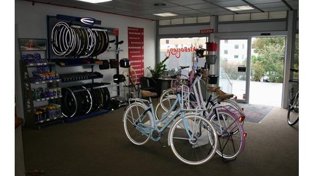 Cykelbutik med flere cykler, dæk og tilbehør præsenteret i et lyst og indbydende lokale.