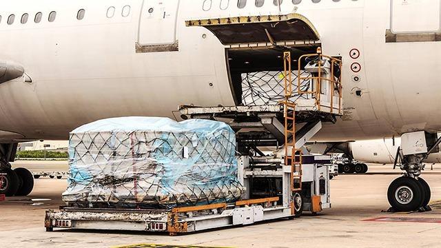 Lastbil med fragtcontainer ved en flyvemaskine på en lufthavn.