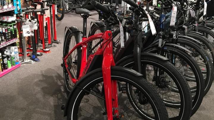 Rød cykel i en cykelbutik, omgivet af flere andre cykler i forskellige farver.