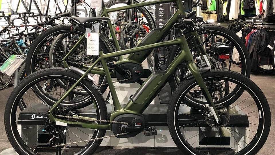 Flere elcykler i en cykelbutik, med fokus på en grøn elcykel foran.