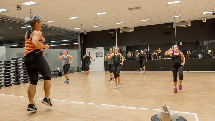 En gruppe mennesker deltager i en fitnessklasse med høj intensitet i et moderne træningslokale.