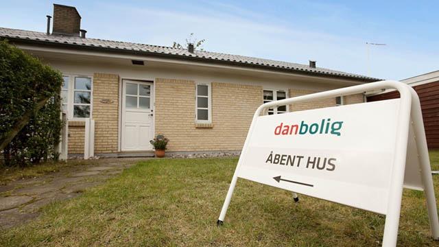 En bolig med en "Åbent Hus" skilt fra danbolig i haven foran huset.