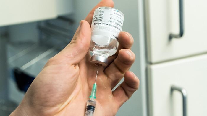 En hånd holder en medicinflaske med en sprøjte klar til at tage medicin.