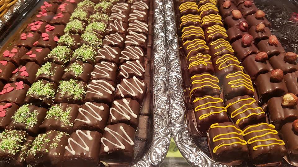 Lækre chokoladekonfekter i forskellige varianter med nødder og pynt på en sølvfad.