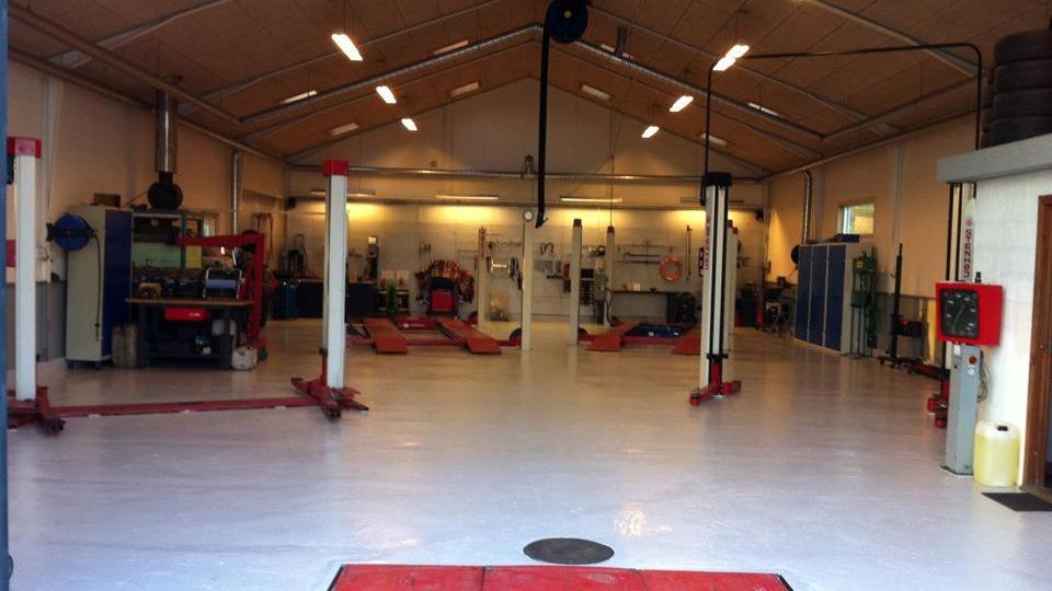 Et bilværksted med løftebukke, værktøjsborde og en ren, lys indendørs plads.