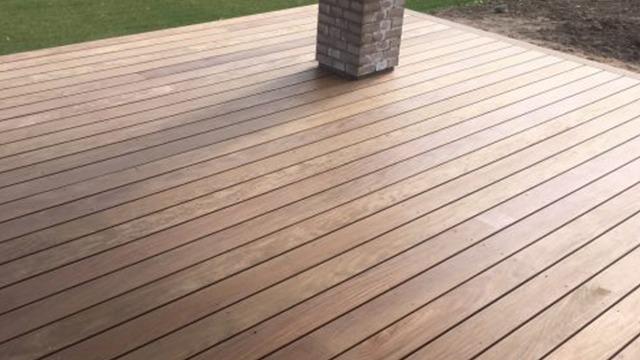 Et lyst trægulv på en terrasse med en murstenssøjle i midten.