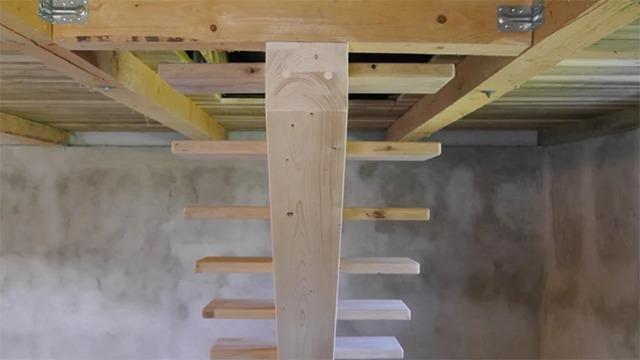 Billede af en træstige med trin, der er fastgjort til en træramme i et rum med betonvægge.