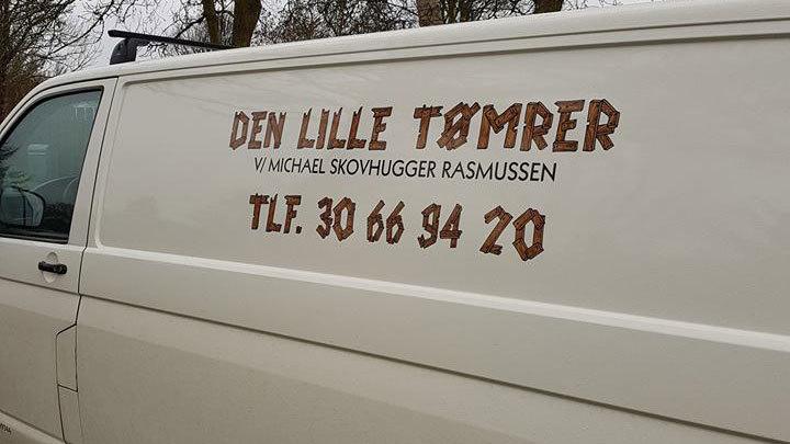 En hvid varevogn med teksten "DEN LILLE TØMRER" og kontaktinformationer på siden.
